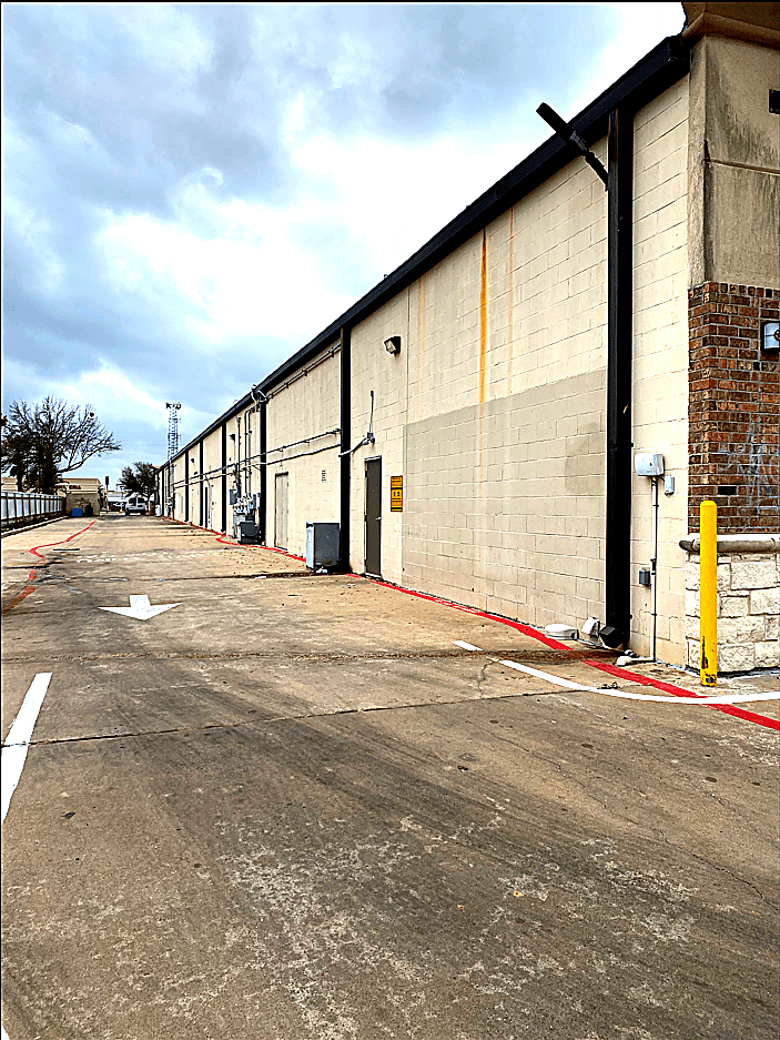 Retail building exterior before repainting — faded and weathered finish
