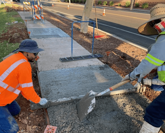 Construction crew finishing concrete sidewalk at commercial property