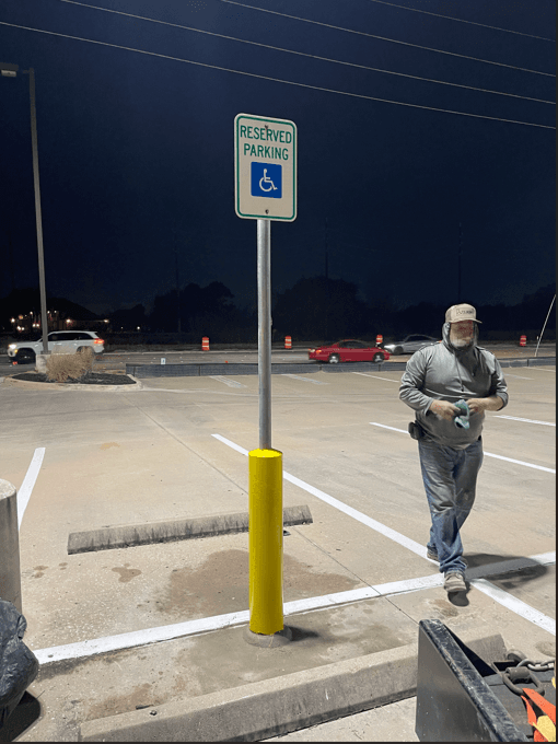 Freshly painted handicap parking sign, pavement marking, and ADA ramp at commercial property