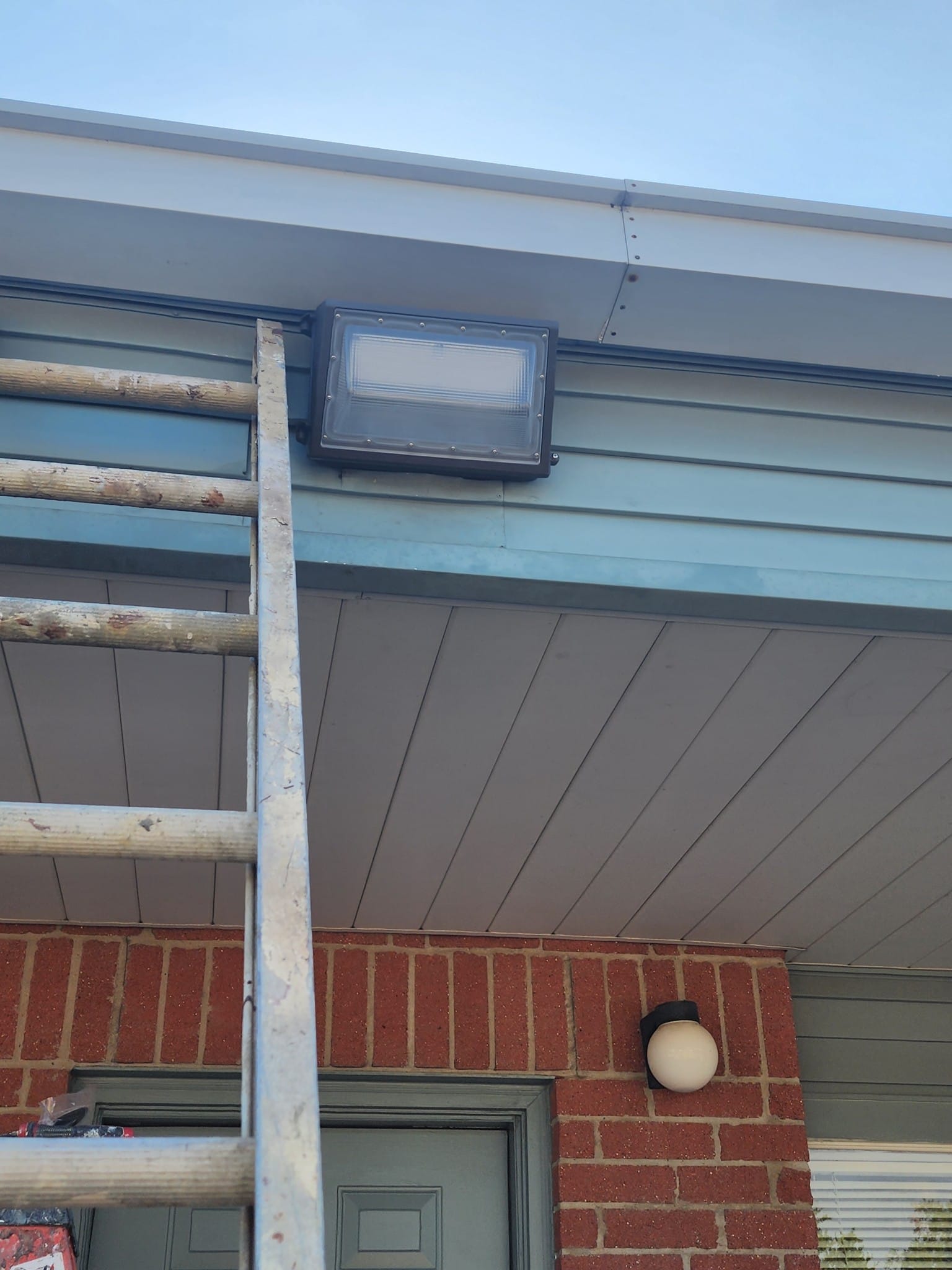 Technician installing wall pack light on commercial building