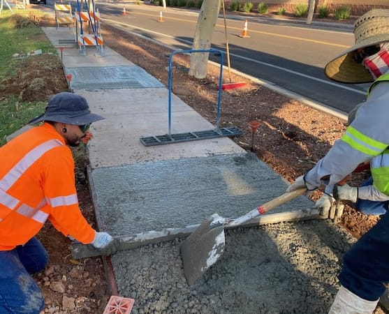 Construction crew finishing concrete sidewalk at commercial property