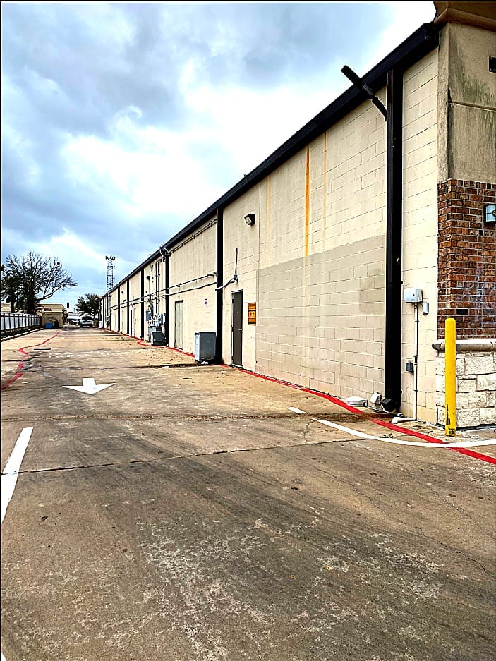 Retail building exterior before repainting — faded and weathered finish